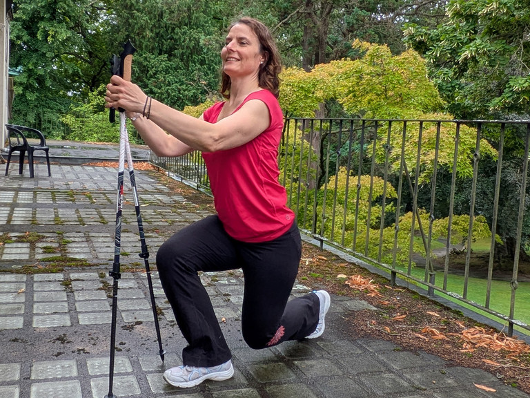 Therapeutin führt Übung mithilfe von Nordic Walking Stöcken aus Therapeutin führt Übung mithilfe von Nordic Walking Stöcken aus