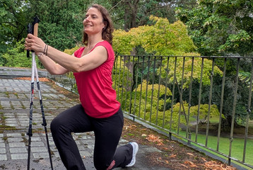 Therapeutin führt Übung mithilfe von Nordic Walking Stöcken aus Therapeutin führt Übung mithilfe von Nordic Walking Stöcken aus
