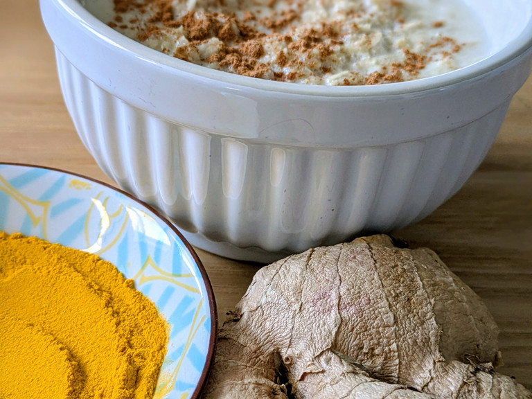 Ingwerwurzel neben Schälchen mit Kurkuma Ingwerwurzel neben Schälchen mit Kurkuma