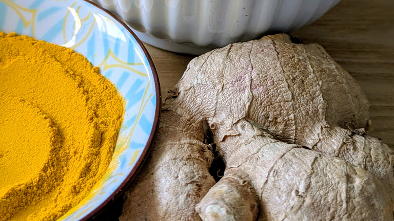 Ingwerwurzel neben Schälchen mit Kurkuma