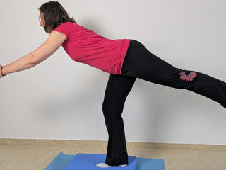 Therapeutin führt Balanceübung auf Pad aus Therapeutin führt Balanceübung auf Pad aus