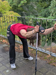 Auf Nordic Walking-Stöcken abstützen und nach vorn gebeugt den Rücken dehnen Auf Nordic Walking-Stöcken abstützen und nach vorn gebeugt den Rücken dehnen
